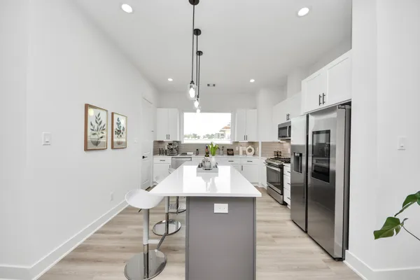 a large kitchen with a table chairs refrigerator and microwave