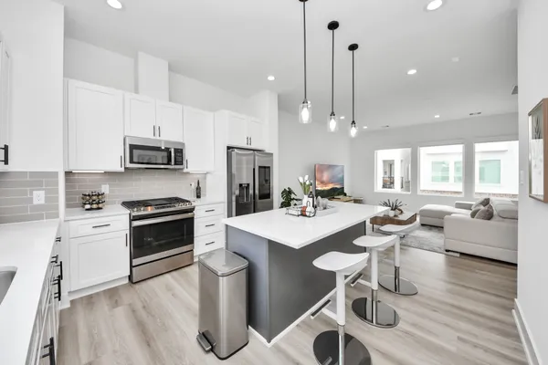 a open kitchen with stainless steel appliances kitchen island granite countertop a stove a sink a refrigerator and a dining table with wooden floor
