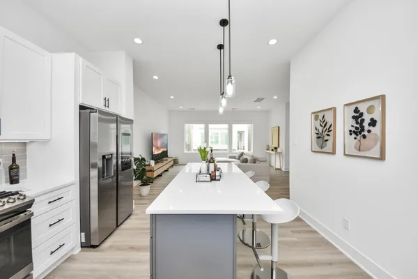 a kitchen with stainless steel appliances kitchen island granite countertop a refrigerator a sink a stove and chairs with wooden floor