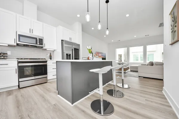 a kitchen with stainless steel appliances granite countertop a stove top oven a sink dishwasher a dining table and chairs with wooden floor