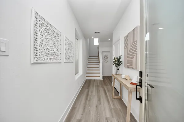 a view of a hallway with stairs and wooden floor
