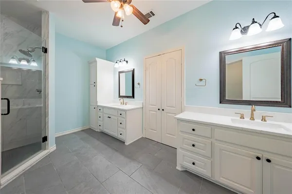 a spacious bathroom with double sink a large mirror and a shower