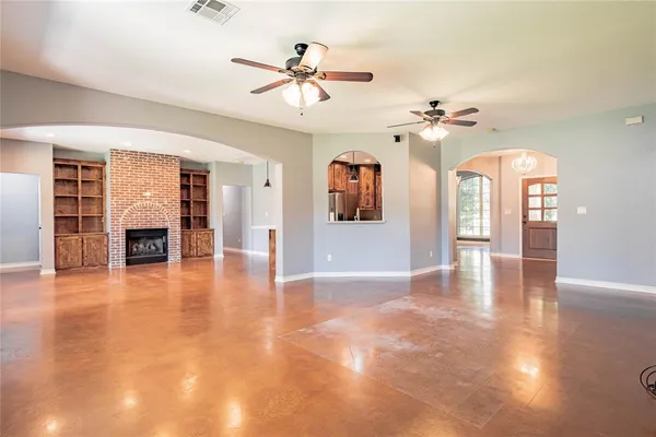a view of an empty room with a fireplace and wooden floor