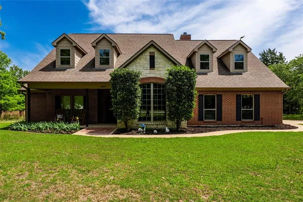 a front view of a house with a yard and trees