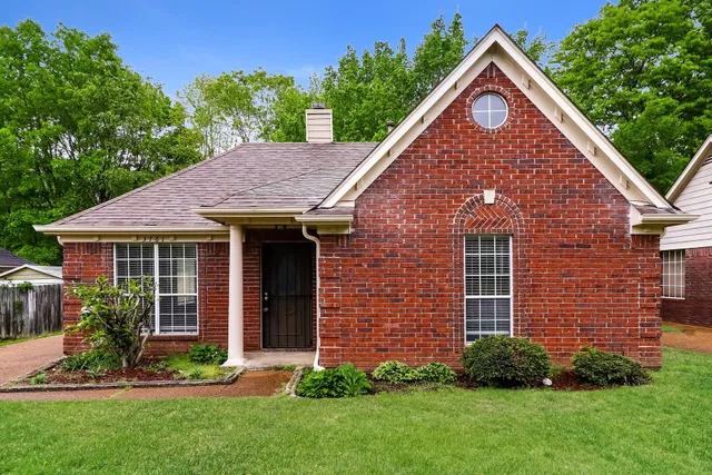 a view of a brick house with a yard potted plants and a table