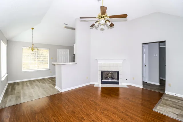 an empty room with wooden floor fireplace and chandelier
