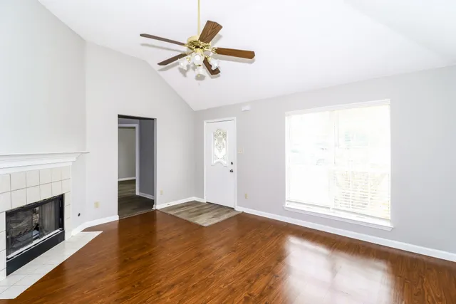 an empty room with windows and fireplace