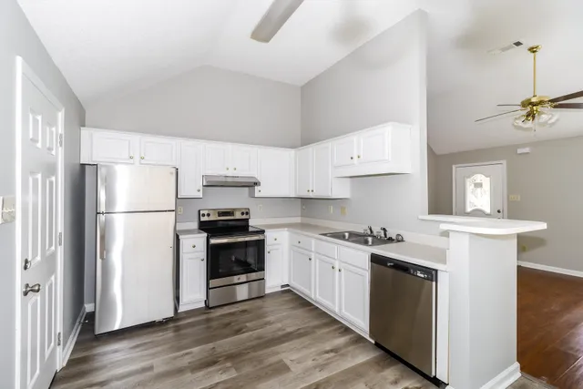 a kitchen with stainless steel appliances granite countertop a stove a refrigerator and a sink with wooden cabinets