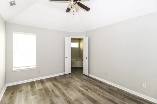 an empty room with a window and a ceiling fan