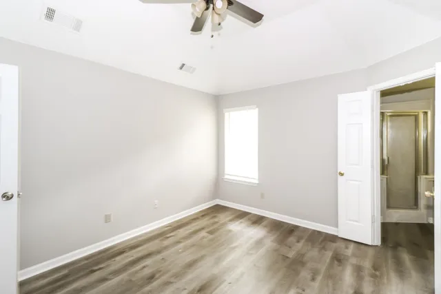 an empty room with a ceiling fan and window
