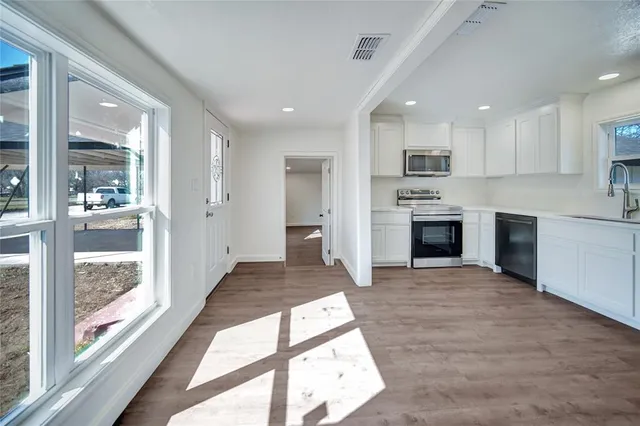 a open kitchen with white cabinets and stainless steel appliances