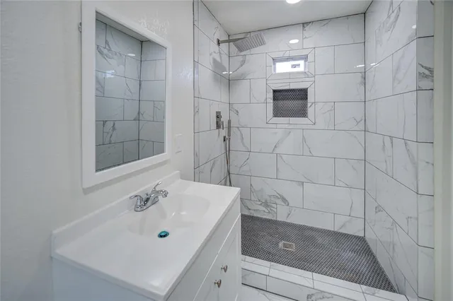 a bathroom with a sink shower and a mirror