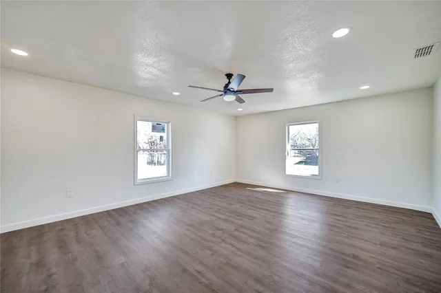 a view of an empty room with a window and wooden floor
