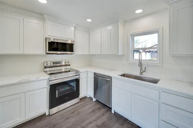 a kitchen with cabinets stainless steel appliances a sink and a window