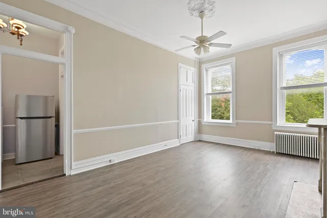 an empty room with wooden floor fan and windows