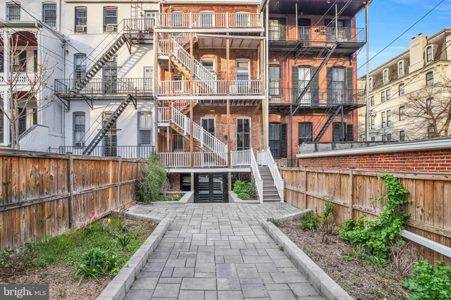 a view of a brick house with a small yard and wooden fence