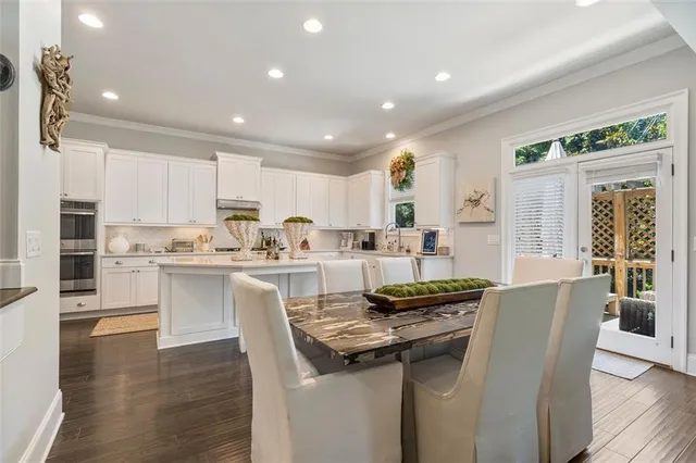 a kitchen with stainless steel appliances granite countertop a table chairs sink and cabinets