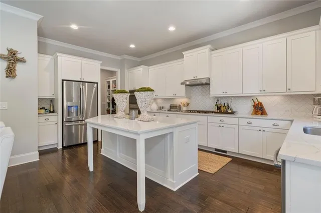 a kitchen with kitchen island granite countertop a table chairs cabinets and wooden floor