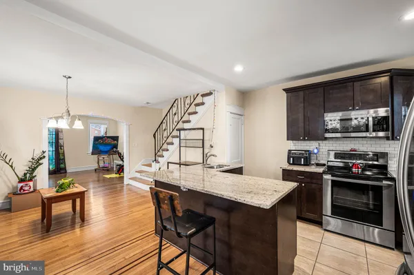 a open kitchen with granite countertop a stove and a wooden floor