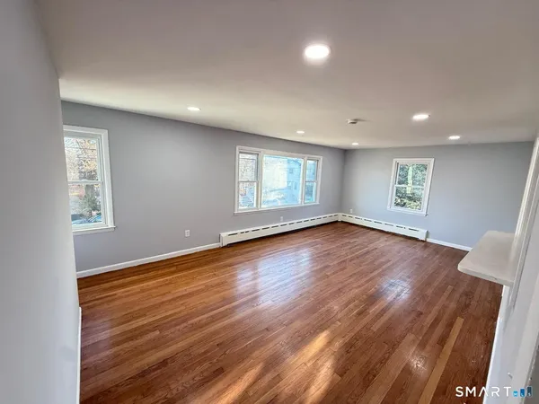 a view of empty room with window and wooden floor