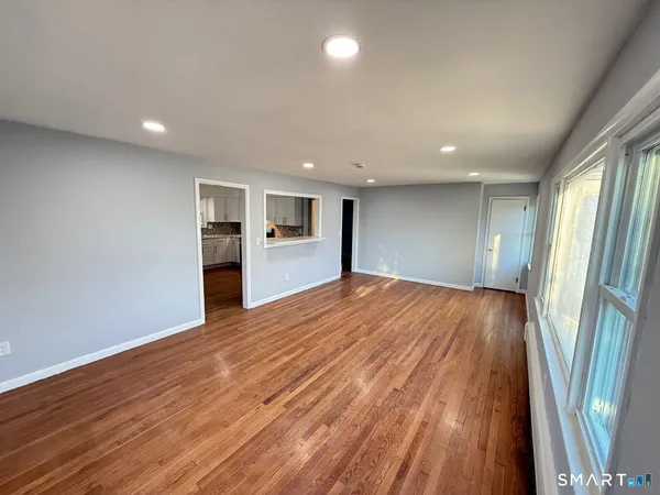 a view of an empty room with wooden floor and a window