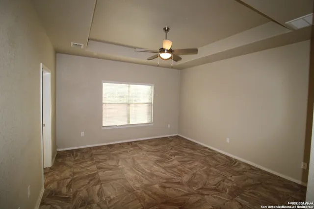 an empty room with a chandelier fan and windows