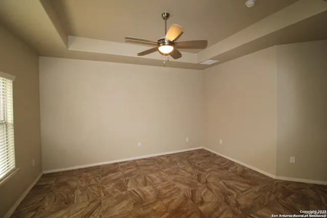 an empty room with a chandelier fan and windows