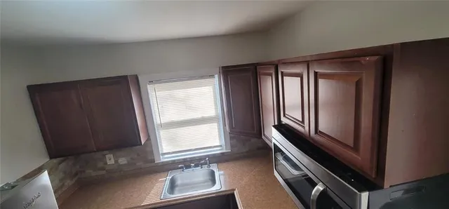 a kitchen with granite countertop a sink stove and microwave