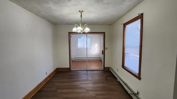 a view of a hallway with wooden floor and chandelier