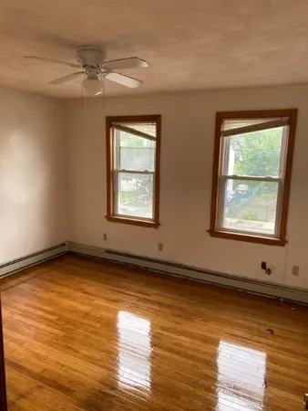 a view of an empty room with wooden floor and a window