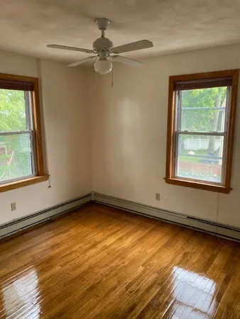a view of an empty room with a window and wooden floor