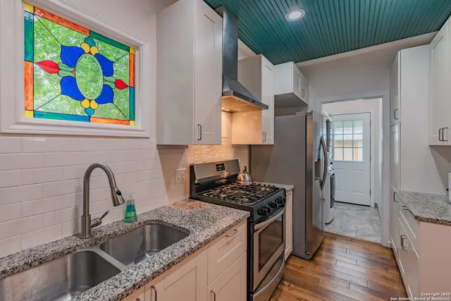 a kitchen that has a sink and a stove with wooden floor