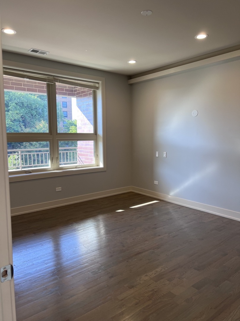 1208 East 64th Street, Unit 2B Chicago, IL 60637 - Photo 13 of 19 an empty room with wooden floor and windows