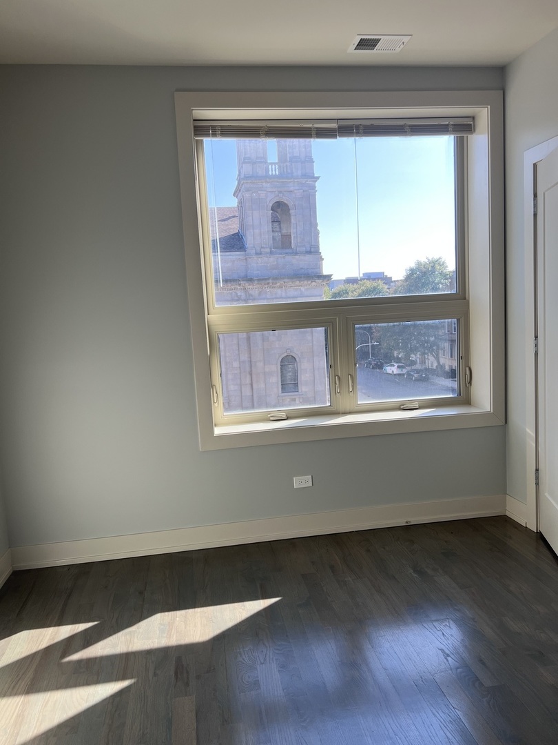 1208 East 64th Street, Unit 2B Chicago, IL 60637 - Photo 16 of 19 a view of an empty room with wooden floor and a window