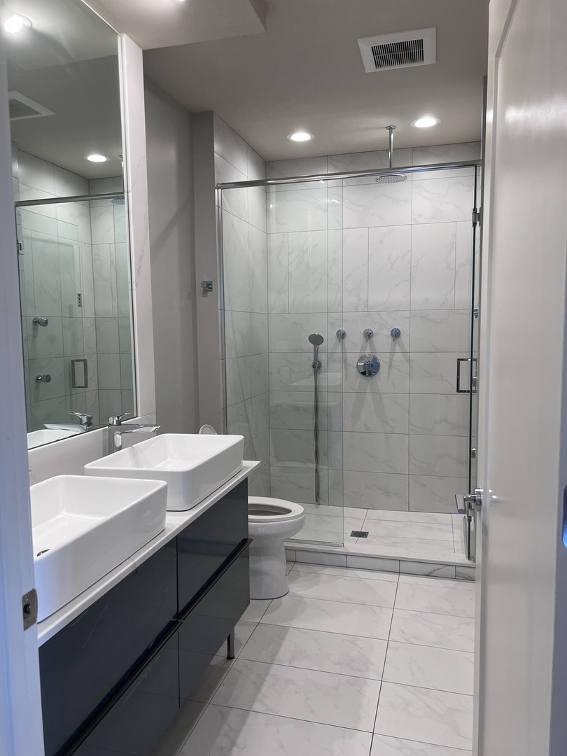 1208 East 64th Street, Unit 2B Chicago, IL 60637 - Photo 9 of 19 a bathroom with a double vanity sink toilet and shower