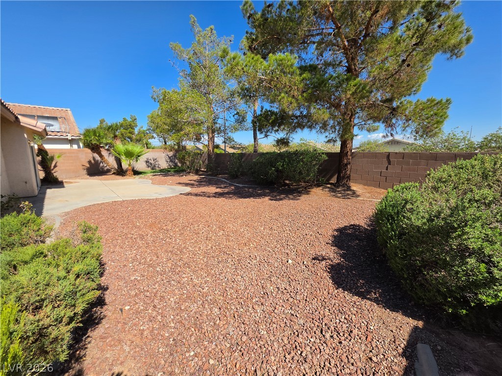 1154 Point Success Avenue Henderson, NV 89014 - Photo 25 of 26 A spacious backyard features a paved patio and lush landscaping, offering a private outdoor retreat.
