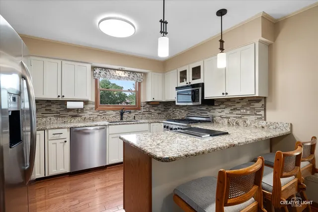 a kitchen with stainless steel appliances granite countertop a kitchen island hardwood floor sink stove and granite counter top