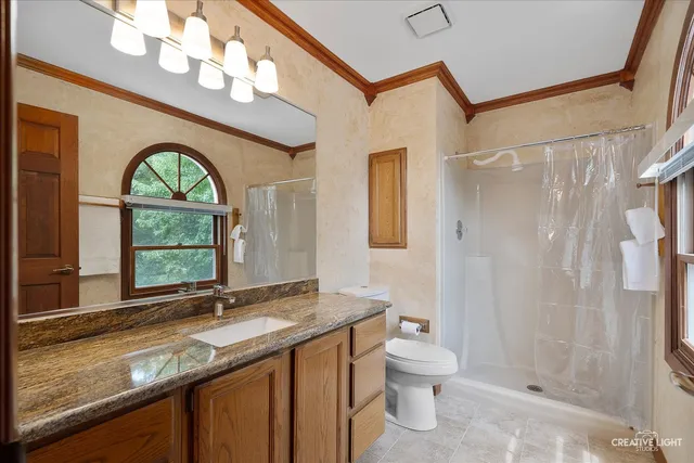 a bathroom with a granite countertop sink toilet a mirror and shower