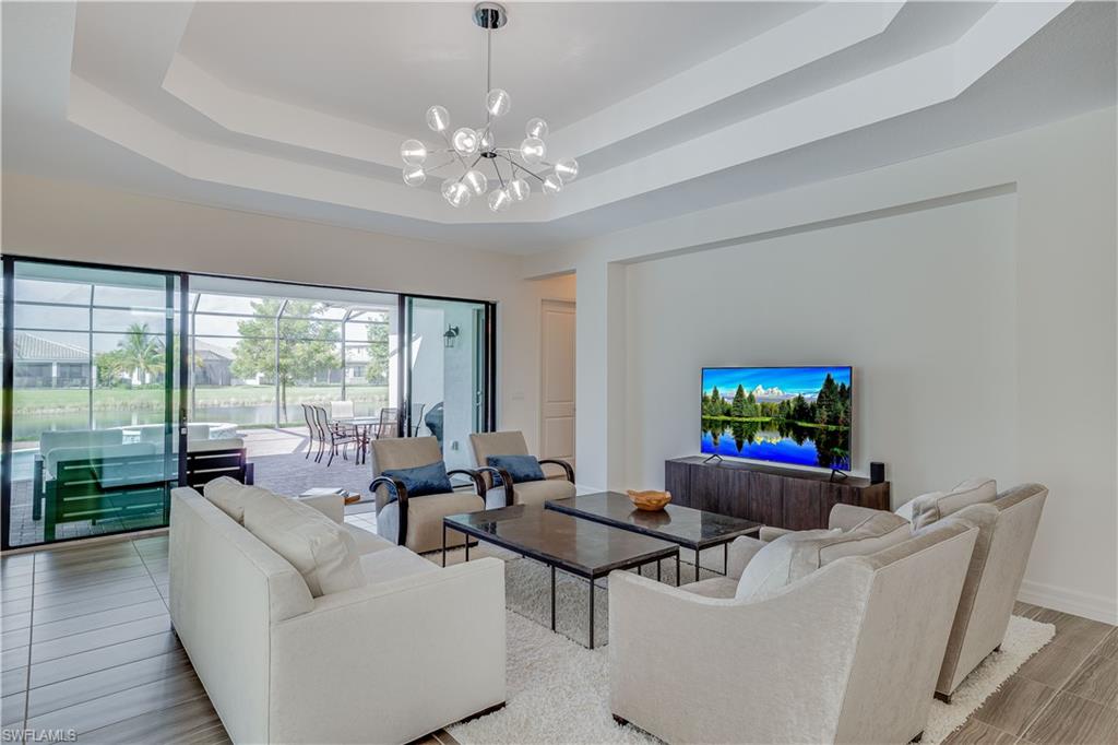 4549 Azalea Drive Naples, FL 34119 - Photo 10 of 25 a living room with furniture a floor to ceiling window and a flat screen tv