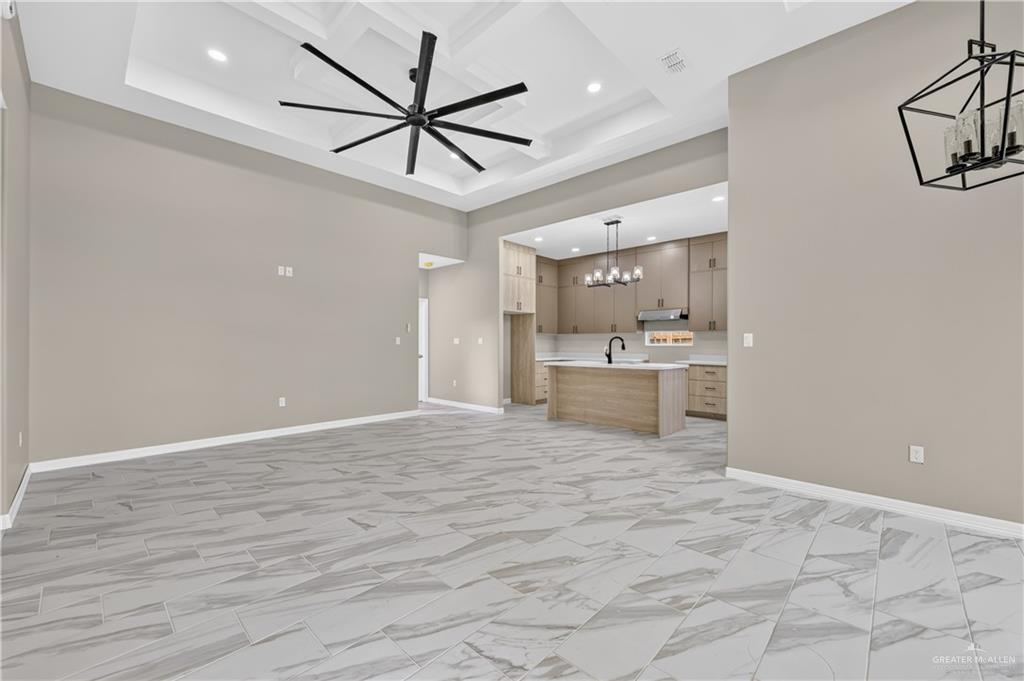 1920 Trinity Street Donna, TX 78537 - Photo 4 of 23 Open-concept living space featuring wood-finish flooring, a tray ceiling with recessed lighting, and a modern ceiling fan
