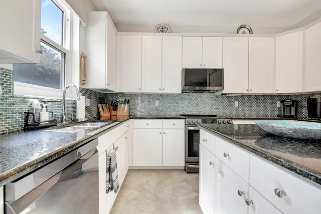a kitchen with granite countertop a sink stove and cabinets