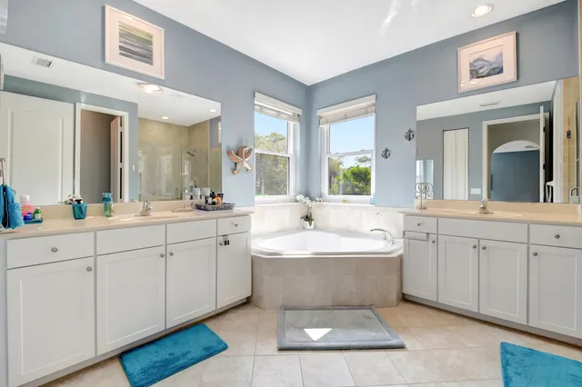 a spacious bathroom with a double vanity sink a mirror and a bathtub
