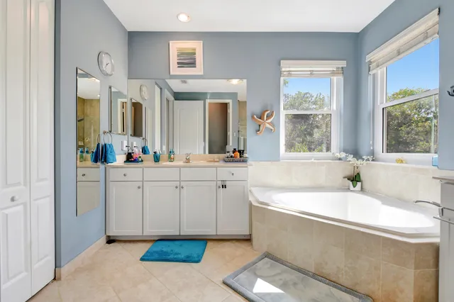 a spacious bathroom with a tub sink and mirror