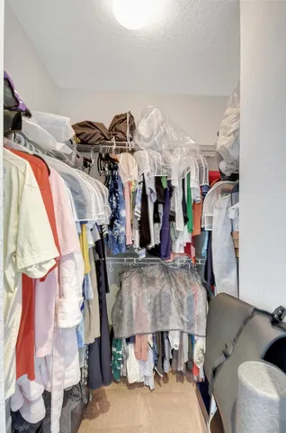a view of walk in closet with clothes and shoes