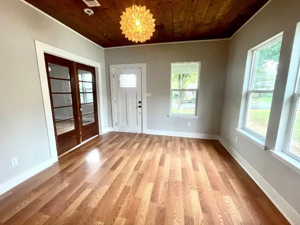 a view of an empty room with wooden floor and a window