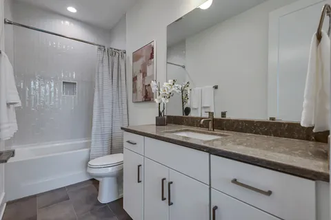 a bathroom with a granite countertop sink a toilet and shower