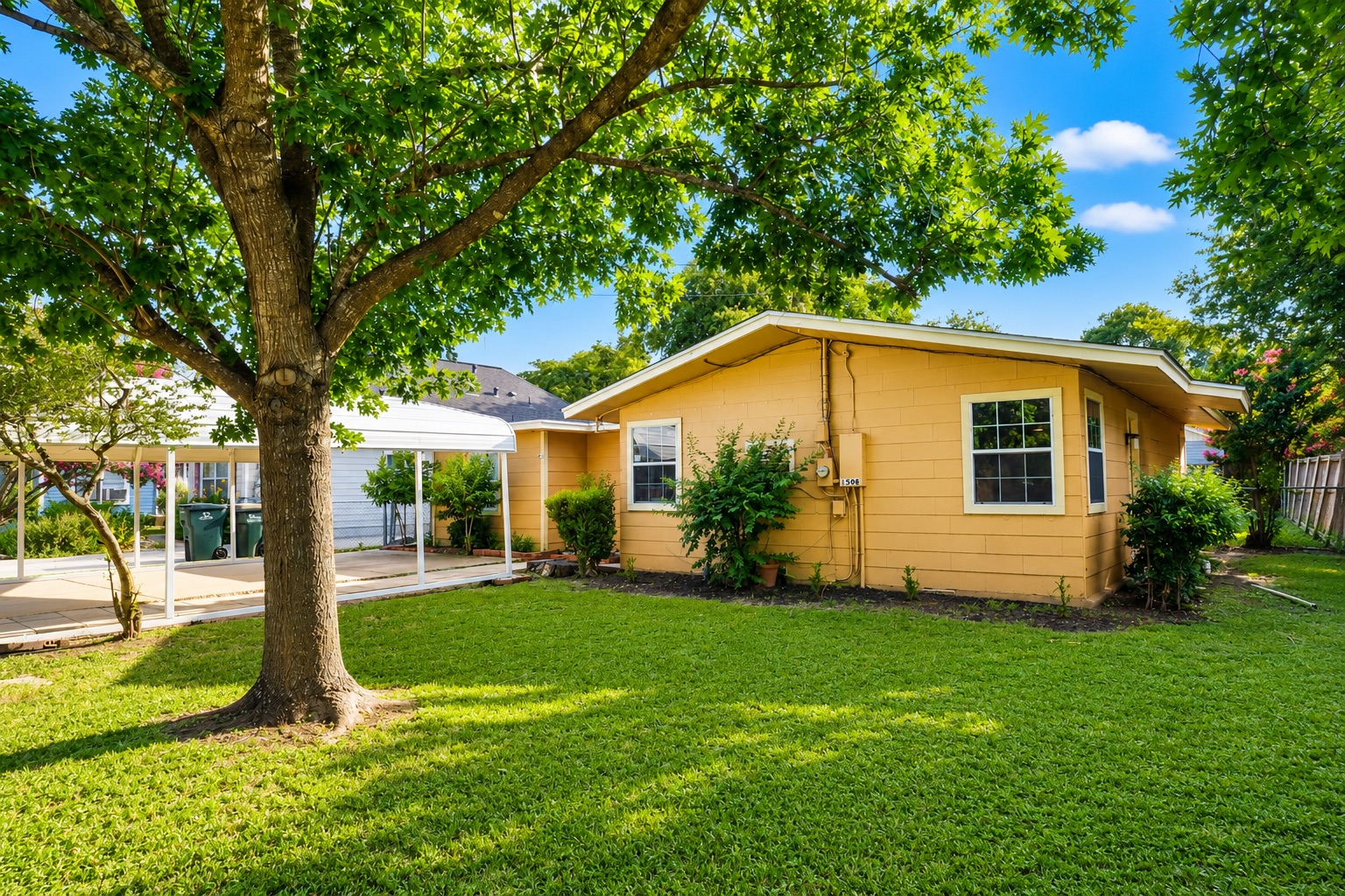 1508 Walnut Street Georgetown, TX 78626 - Photo 2 of 37 A well-maintained lawn embraces a welcoming residence with a convenient carport and lush surrounding greenery.