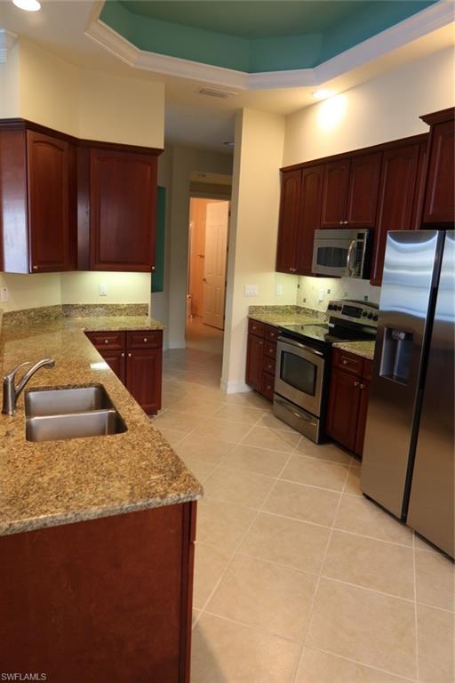 7168 Lemuria Circle, Unit 1701 Naples, FL 34109 - Photo 14 of 39 Kitchen featuring wood-finish cabinetry, stone countertops, and a stainless steel appliance suite