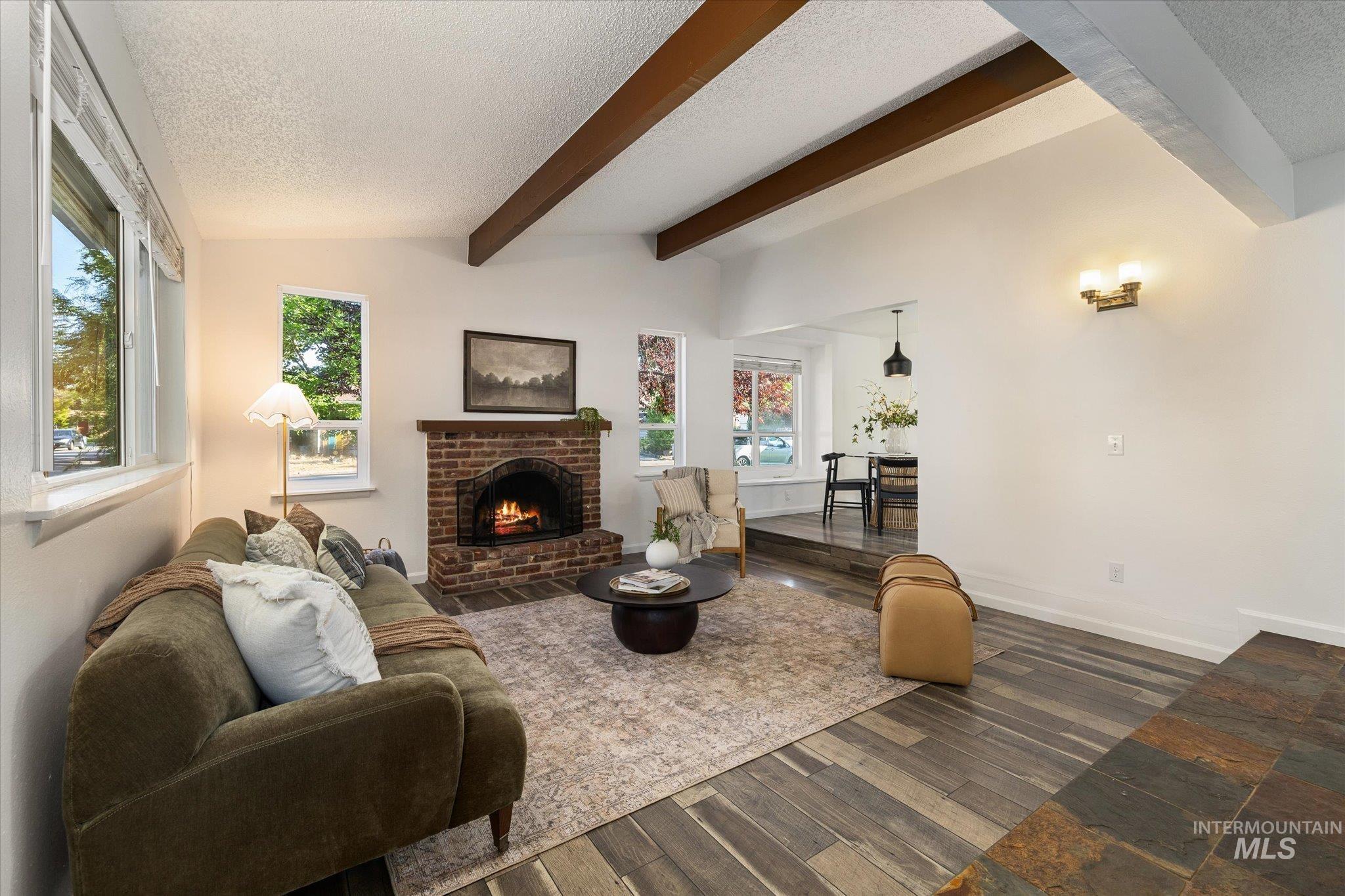 2302 Pendleton Street Boise, ID 83705 - Photo 4 of 35 Living area featuring a brick fireplace, vaulted ceilings with exposed wood beams, and multiple windows