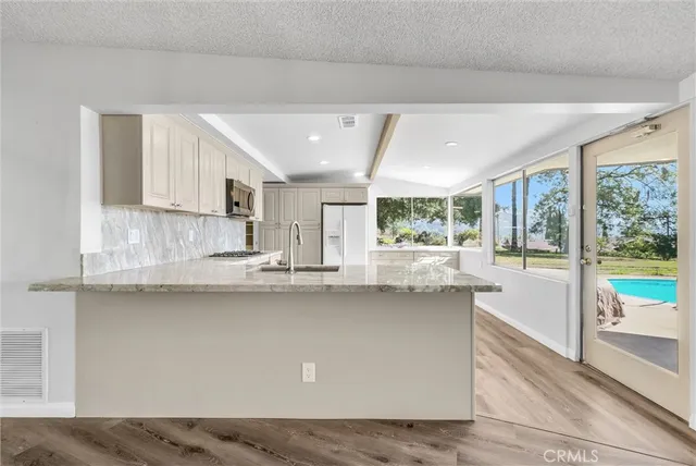 a large white kitchen with stainless steel appliances granite countertop a sink and cabinets
